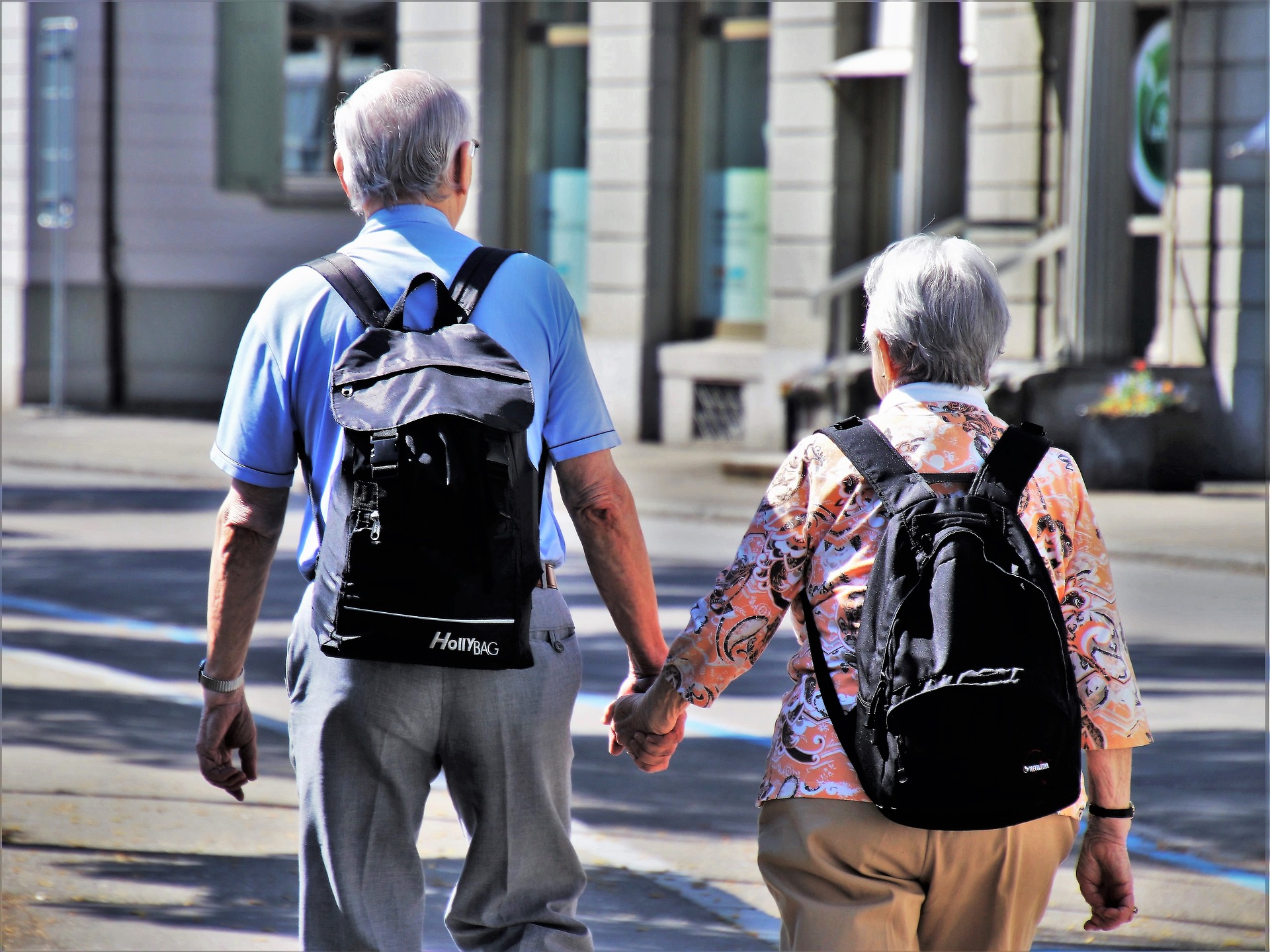 Älteres Paar läuft Hand in Hand und mit Rucksack durch eine Stadt
